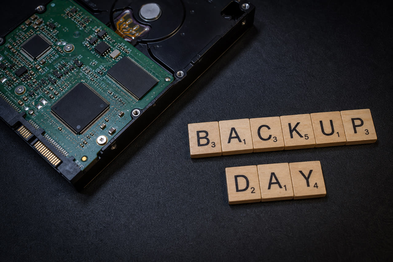 Hard drive circuit board beside wooden tiles spelling Backup Day